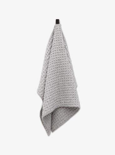 Gray textured towel hanging on a black hook against a white background
